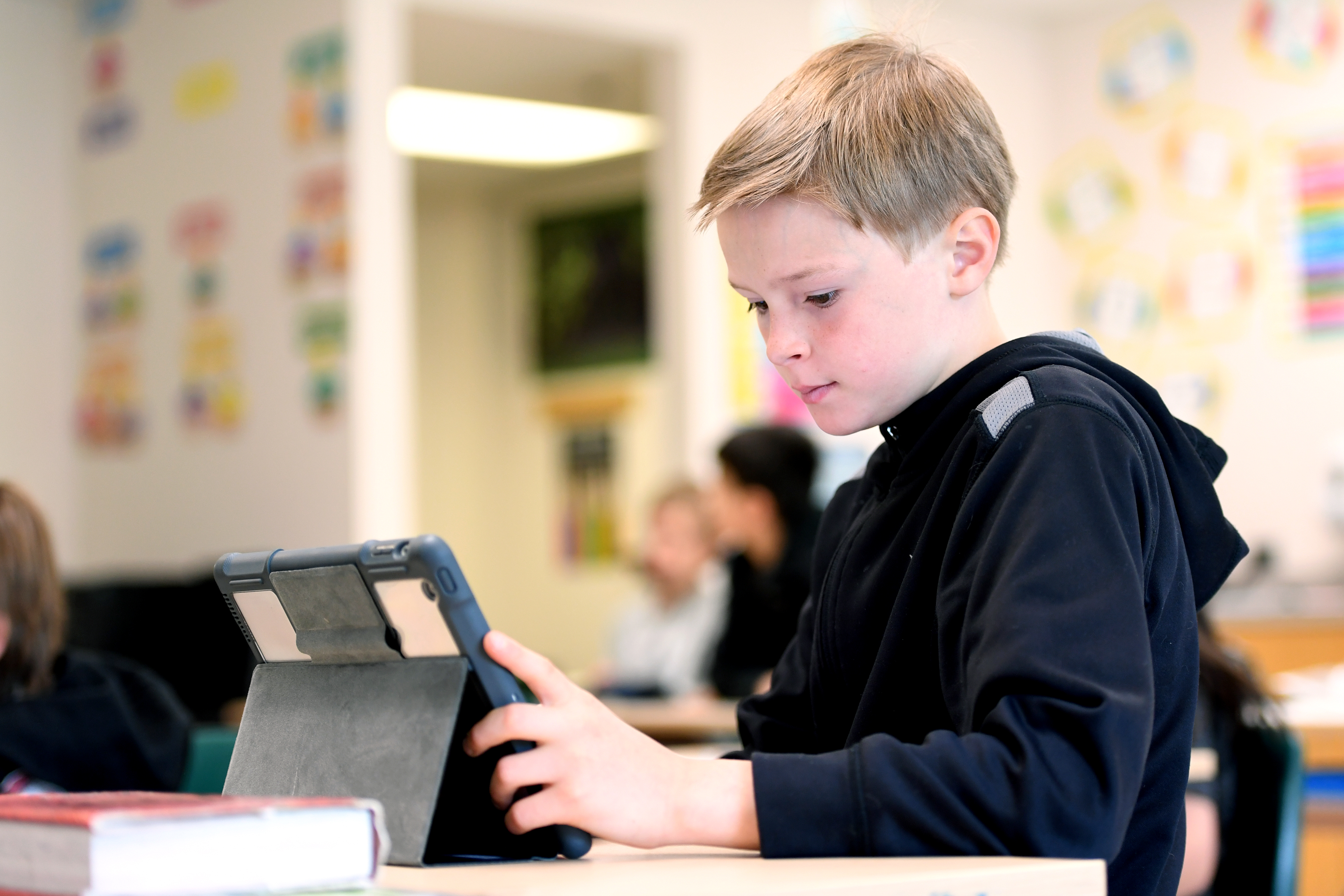 Boy wearing black hoody looking at iPad